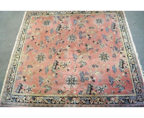 A Chinese style carpet with an overall pattern of repeating motifs on a pink ground within a wide border, 325cm x 370cm