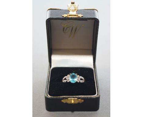 A yellow and white metal ring. Principally set with an oval faceted cut blue topaz and finished with single cut diamonds. Hal