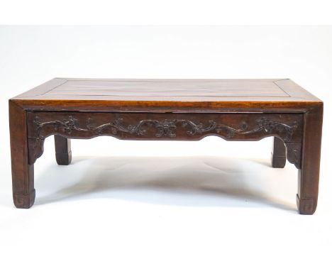 A Chinese rosewood low rectangular table, with scroll shaped aprons, carved with flower heads and tendrils, the square legs t