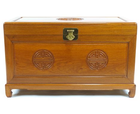A Chinese hardwood chest, the hinged top with brass lock above a carved panelled front, on low scroll feet, 61cm high x 104cm