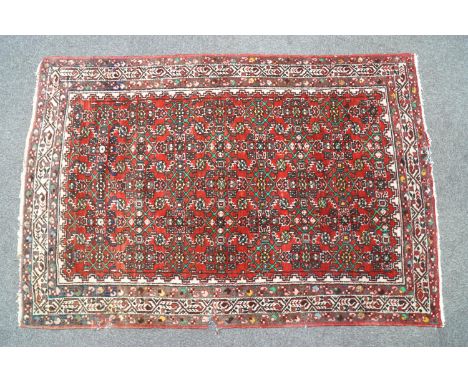 A handmade Persian Mashad carpet, circa 1930-1940, with continuous strapwork motifs on a red ground in natural organic colour