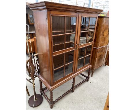 AN EARLY 20TH CENTURY MAHOGANY TWO DOOR GLAZED DISPLAY CABINET ON OPEN BOBBIN TURNED BASE, 45" WIDE 