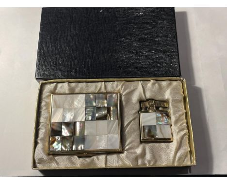 A VINTAGE BOXED SET COMPRISING OF A MOTHER OF PEARL HILTON LIGHTER AND A MATCHING MIRRORED COMPACT 