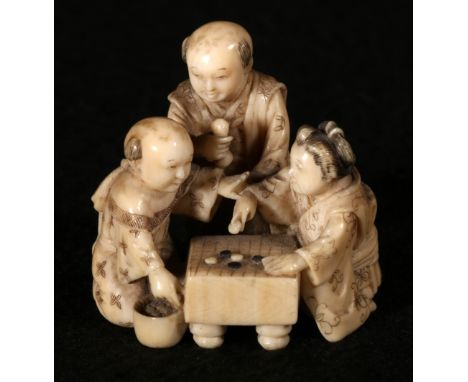 Japanese carved ivory okimono of a woman and a boy playing go, a man standing over them, part inked, 4.5cm CONDITION REPORT: 