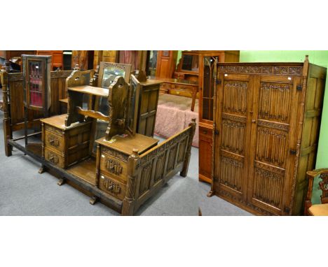 A 1930's linen fold carved oak bedroom suite; comprising wardrobe, dressing table, bedside cabinet, dressing table mirror, st