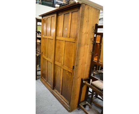 A 20th century panelled oak wardrobe with twin sliding doors 