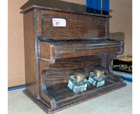 A 1920's oak novelty inkstand in the form of a piano, with stationery compartment, 30cm wide.