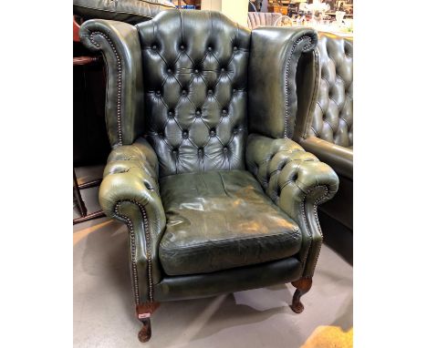 An antique green high wing back chesterfield chair with button back and arms