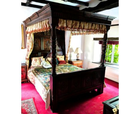 An oak four poster bed with solid canopy above, carved detail to foot and head, with turned supports. Length 217 x height 210