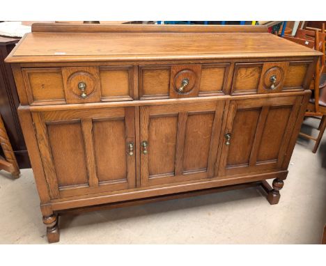 A golden oak sideboard with three cupboards and three drawers below.