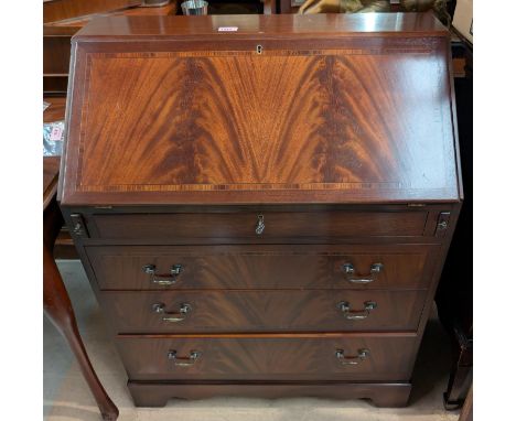 A reproduction mahogany bureau with fall front, drop handles frieze drawer and three others drawers