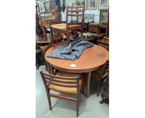 A 1960's circular extending teak dining table and four low ladder back chairs.