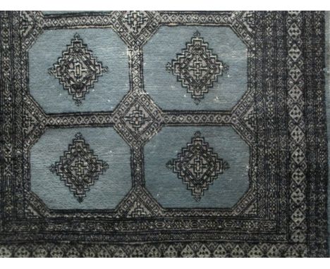 A WOOL RUG the light blue ground with central panels filled with geometric patterns within a conforming border 118cm x 176cm