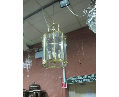 A GILT BRASS AND GLAZED FOUR LIGHT HALL LANTERN of cylinderical form hung with ribbon tied swags and pierced apron 83cm x 40c