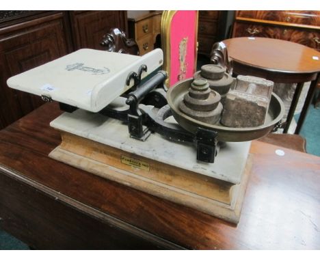 A GROCERS WEIGHING SCALES the glazed China tray and circular brass pan on a cast iron and marble base raised on an oak plinth