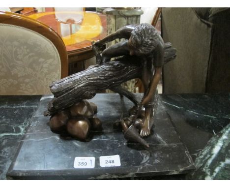A BRONZE FIGURE modelled as a young boy seated on a tree trunk shown fishing raised on a black vein marble base 25cm x 35cm x