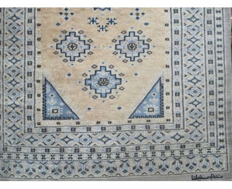 A WOOL RUG the light pink and blue ground the central panels filled with stylized flowerheads within a conforming border 168c