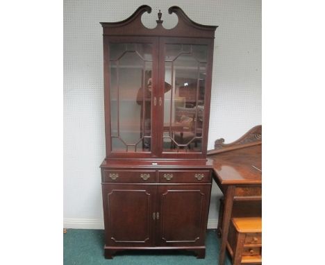 A GEORGIAN STYLE MAHOGANY BOOKCASE the swan neck pediment above a pair of astragal glazed doors the base with two short drawe
