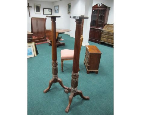A PAIR OF MAHOGANY TORCHERES each with a circular dish top above a fluted and foliate carved column on tripod support with cl