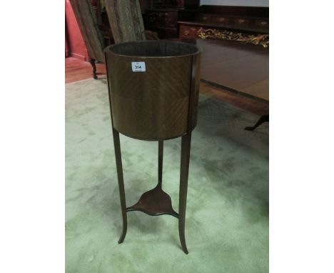 AN EDWARDIAN MAHOGANY PLANTER of cylindrical form on moulded legs joined by a shaped under tier