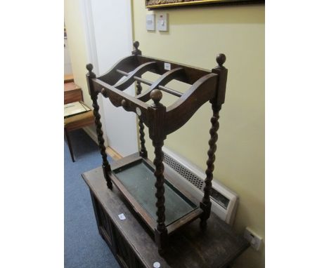AN OAK SIX COMPARTMENT STICK STAND c.1950 the rectangular moulded top raised on spiral twist supports with drip pan on ball f