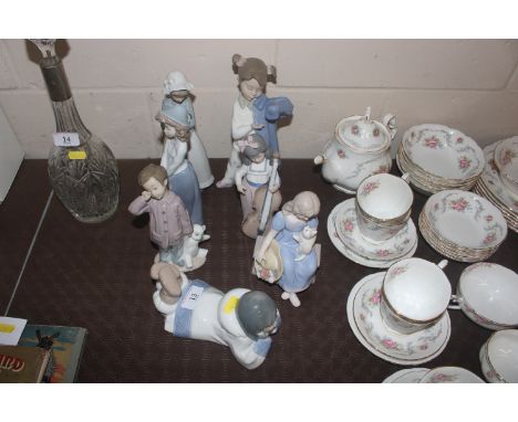 Six Nao figurines and a Nao style figure, young girl with kitten seated on a bench