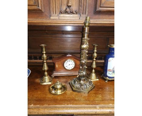 An Edwardian mahogany cased mantel clock; an ornate brass table lamp; a pair of Victorian brass candlesticks; a brass inkwell