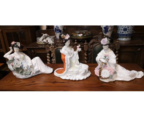 Three oriental porcelain figures of reclining females, decorated with flowers 