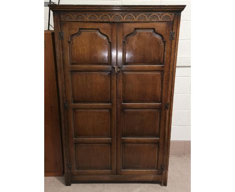 A 1930's oak double door wardrobe in the manner of Titmarsh and Goodwin with carved panel doors