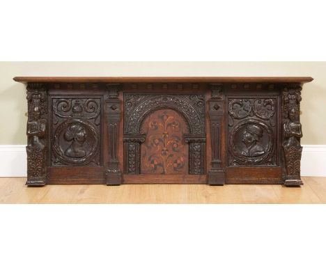 An antique carved oak overmantle, with central 17th Century inlaid panel, a profile panel to either side and flanked by decor