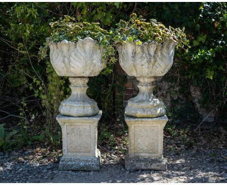 A pair of cast reconstituted stone garden urns decorated with acanthus leaves on octagonal bases and with plinths decorated w