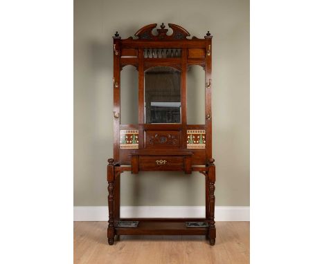 A Victorian hall stand with central mirror flanked by brass coat hooks above carved and tile inserts, single drawer and base 