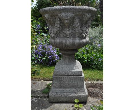 A cast reconstituted stone garden urn decorated with masks and fruiting swags, on fluted square pedestal base, 56cm diameter,