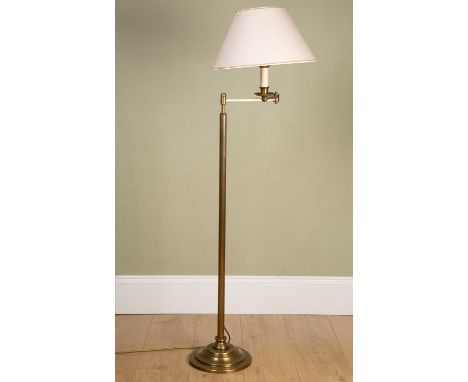 A contemporary brass floor standing adjustable reading lamp, on circular spreading base, the base 23cm diameter, the lamp 140