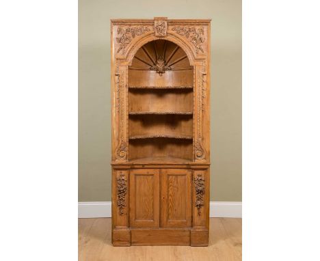 A George III-style pine corner display shelf, the arching recess with barrelled back and shaped shelves over panelled cupboar