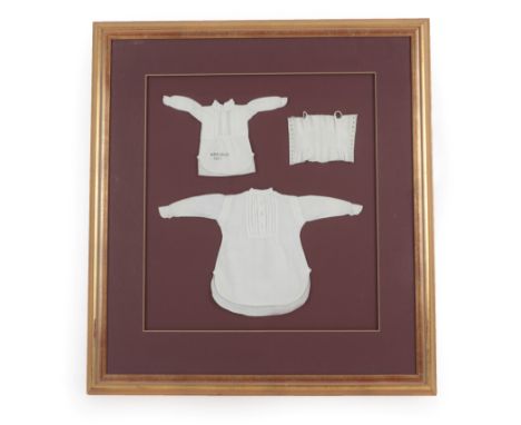 A Framed Display of Three 19th Century School Sewing Samples, including a white cotton corset with button holes, gentleman's 