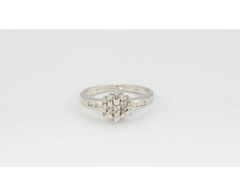 A 9ct white gold diamond set cluster ring with diamond set shoulders, (K).