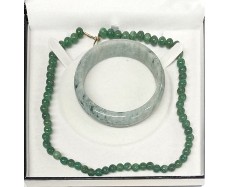 A boxed single strand necklace of 7.5mm jade beads, L. 46cm, together with a jade bangle.