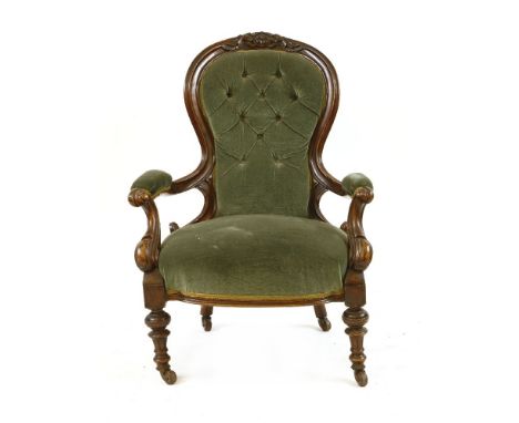 A Victorian carved mahogany gentleman's armchair, the button spoon back above stuffover seat on turned feet, 95cm high