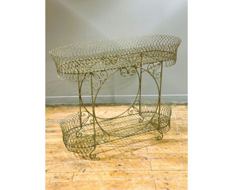 A 19thc wrought ironwork elongated oval two tier planter, with carry handle to each side, putty green painted finish, on scro
