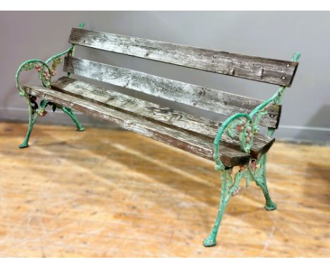 A 19th century cast iron long garden bench, the painted ends cast as naturalistic branch, berry and leaf, with pine plank bac