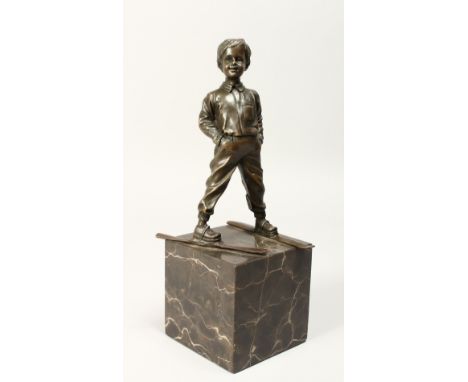 AFTER FERDINAND PRIESS (1882 - 1943) GERMAN A BRONZE FIGURE OF A YOUNG BOY ON SKIS, his hands in his pockets, mounted on a ma