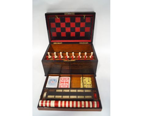 A Victorian rosewood games compendium with ivory chess and draughts sets, cribbage board, playing cards, two dice shakers and