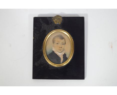 An early 19th century portrait miniature of a young boy wearing a blue jacket, Watercolour on card, 6cm x 4.5cm, oval