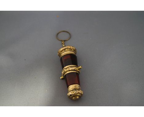 A cannon shaped red glass scent bottle, with an unmarked gilded embossed hinged cover to the vinaigrette at one end, this als
