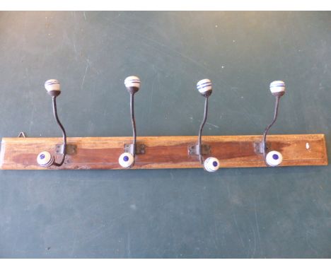 Vintage wall hanging coat rack with cast metal hooks leading to china blue and white balls.