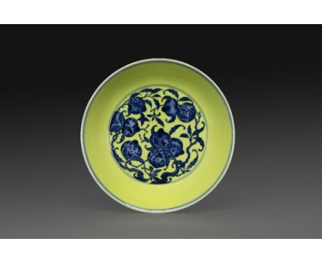IMPORTANT PLAT CIRCULAIREen porcelaine, émaillée bleu et blanc en réserve sur fond jaune, à décor central de neuf pêches de l