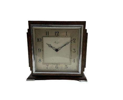 An Art Deco mantle clock retailed by Kendal & Dent London, in a square oak case on raised feet, chrome inset bezel and glass 