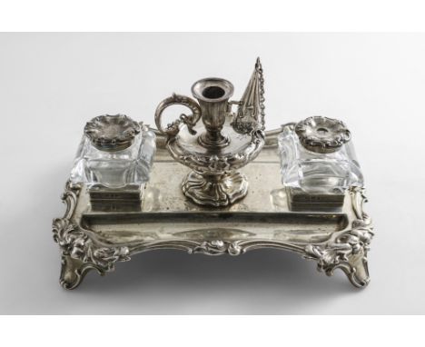 A VICTORIAN SILVER INKSTAND of shaped rectangular outline with a floral scroll border, two mounted cut-glass ink bottles and 