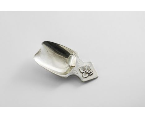 AN EARLY 20TH CENTURY CADDY SPOON in the form of a scoop with a shaped lug handle, decorated in relief with a trefoil leaf an